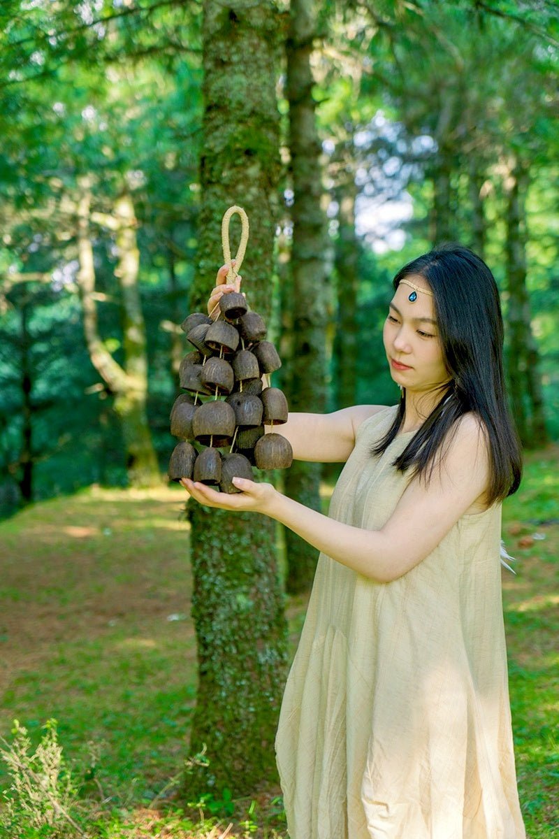 Woman holding a traditional bell悬挂器 in a forest setting